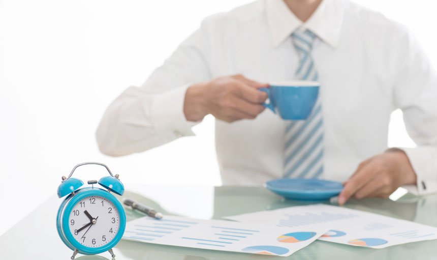 Gestión-del-Tiempo-y-Productividad Hombre tomando cafe con reloj en su escritorio