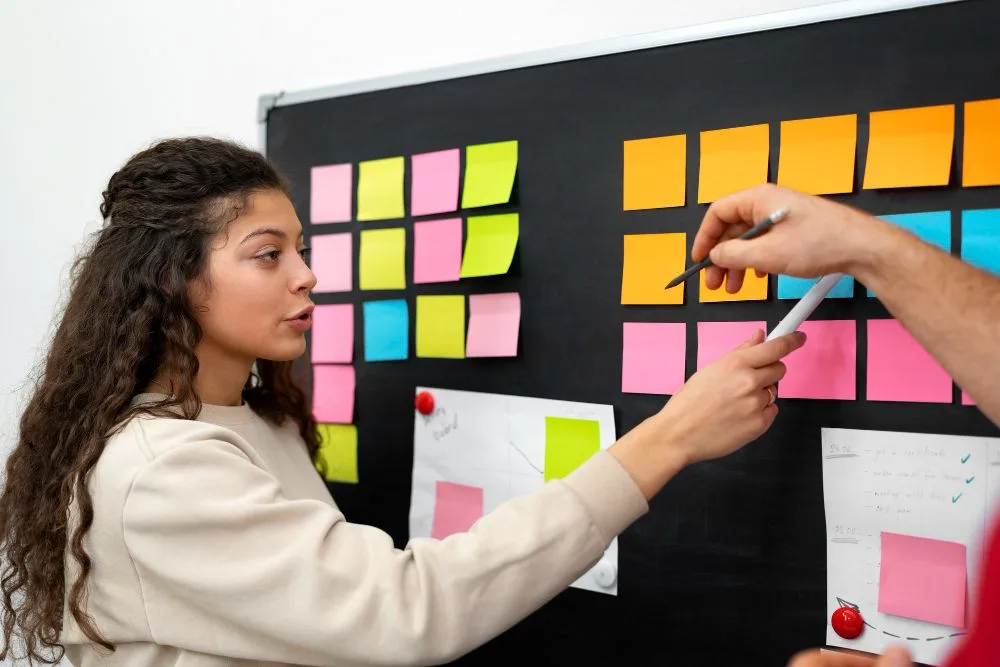 Mujer frente a tablero con post it de colores . Coach trabajo personalizado
