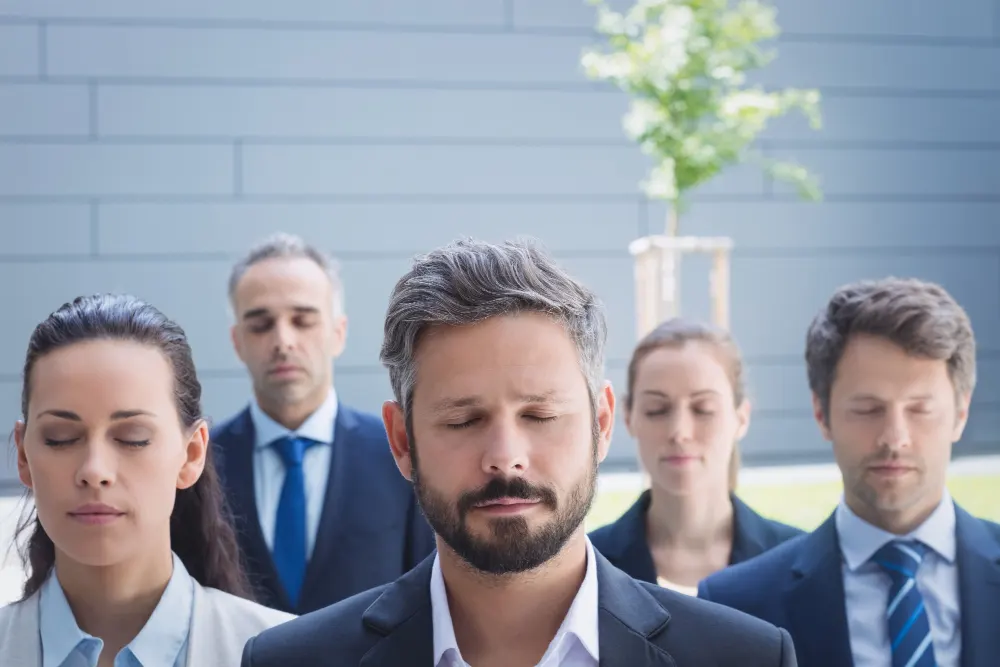 Grupo de trabajo juntos con los ojos cerrados mostrando liderazgo transformacional